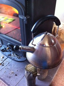 Kettle keeping warm on logs drying next to burner